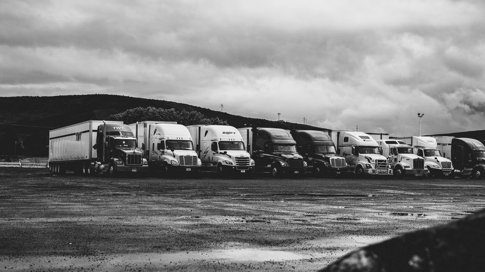 Freight trucks lined up at a logistics depot loading bay — Vehicle Tracking & Cross-Border Supply Chain Advisory